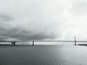 Bridge over river against cloudy sky