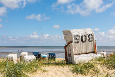 Hooded chairs on beach against sky