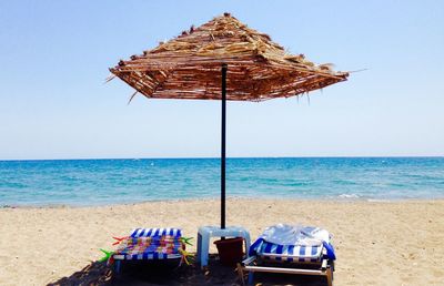 Chairs on beach against clear sky