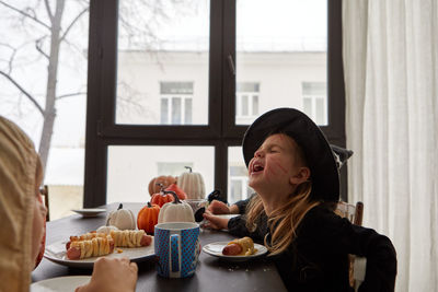 Funny girl in halloween costume eating at table