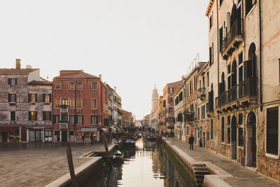 Canal in city against clear sky