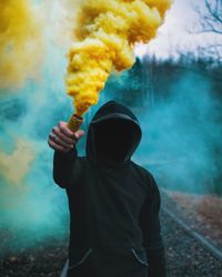 Close-up of man holding cigarette against sky