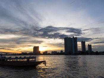 Scenic view of sea by buildings against sky during sunset