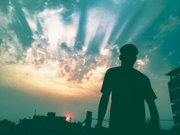 Rear view of silhouette man standing against sky during sunset