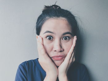 Close-up portrait of shocked woman against wall