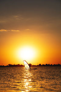 Female windsurfer silhouette at lake sunset. beautiful beach landscape. summer water sports