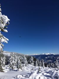 Scenic view of snowcapped dolomites mountains against clear blue sky with a helicopter in winter