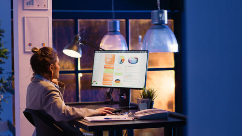 Rear view of woman using laptop at office