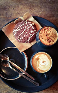 High angle view of coffee cups and cookie in serving tray