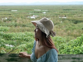 Side view of woman looking away while standing on field