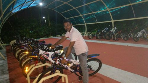 Man standing by bicycle at night