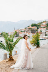 Woman standing on road near palm tree