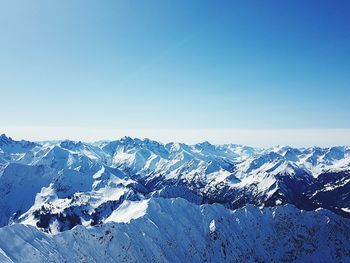 Scenic view of snowcapped mountains against clear blue sky