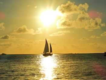 Sailboat sailing on sea against sky during sunset