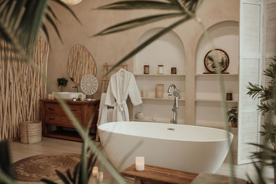 Luxury interior of big bathroom at modern african style with oval bathtub in natural lighting