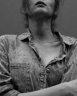 Midsection of woman with freckle against gray background