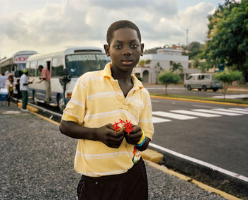 Portrait of young woman standing on road in city