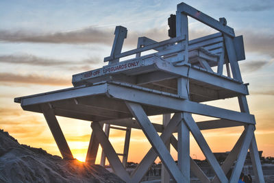 Low angle view of metallic structure against sky during sunset