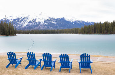 Empty chairs and tables arranged in front of calm blue sea