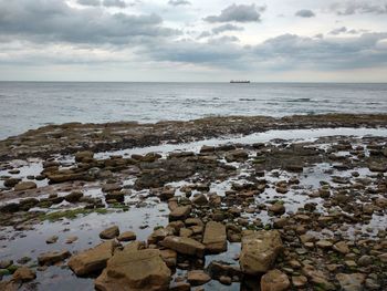 Scenic view of beach against cloudy sky