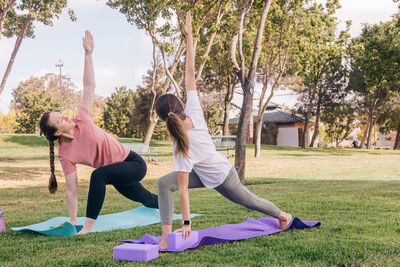 Two young women in the park doing yoga in the morning. exercising outdoors, healthy lifestyle