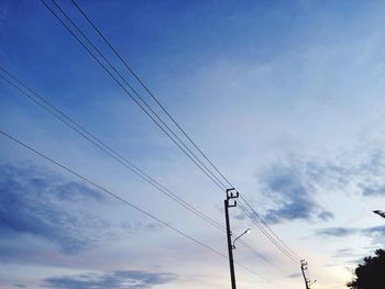 Low angle view of electricity pylon against blue sky