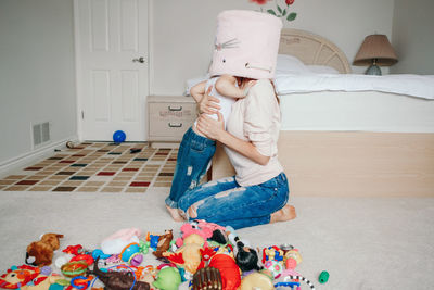 Mother parent playing with baby toddler in bedroom. mom and kid boy girl with toy bin on heads