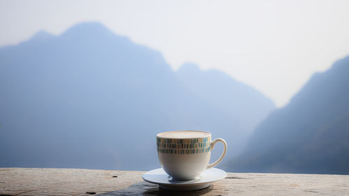 Coffee cup on table against mountains