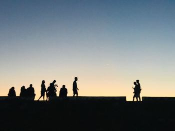 Silhouette people against clear sky during sunset