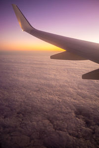 Airplane wing against sky during sunset