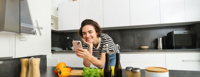 Portrait of young woman using mobile phone at home