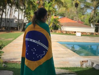 Woman standing by swimming pool against trees