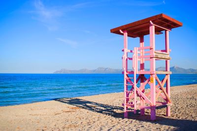 Lifeguard hut on beach against blue sky during sunny day