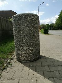 Stone wall by street in city against sky