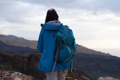 Rear view of man standing on mountain against sky