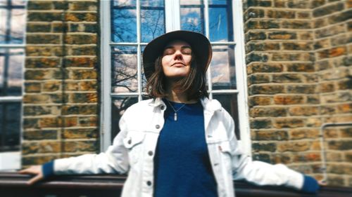 Young woman wearing hat against building