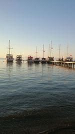 Sailboats moored on sea against clear sky