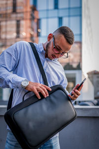 Portrait of young handsome businessman with eyeglasses and shirt walking in the street