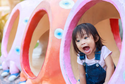 Baby girl shouting while sitting in jungle gym