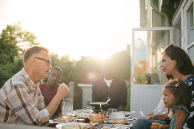 Multi-generation family having lunch at table on porch during sunny day