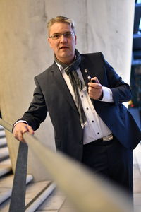 Portrait of businessman holding smoking pipe while standing on staircase