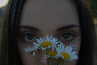Close-up portrait of beautiful woman holding daises