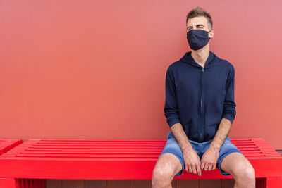 Portrait of man sitting against red wall