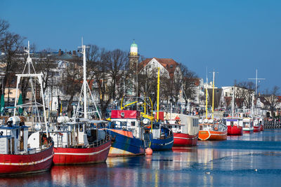 Boats moored at harbor in city against clear sky