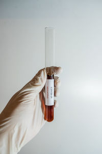 Close-up of hand holding bottle against white background