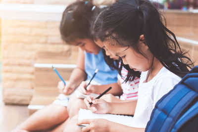 Girls studying while sitting on chair