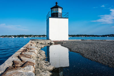 Lighthouse by sea against sky
