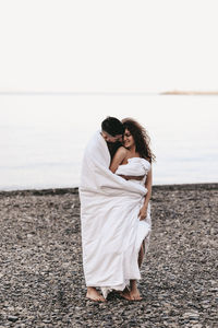 Rear view of couple on beach against sky