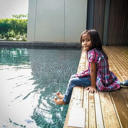 Portrait of smiling girl sitting by swimming pool