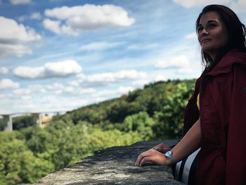 Smiling young woman looking at view against sky